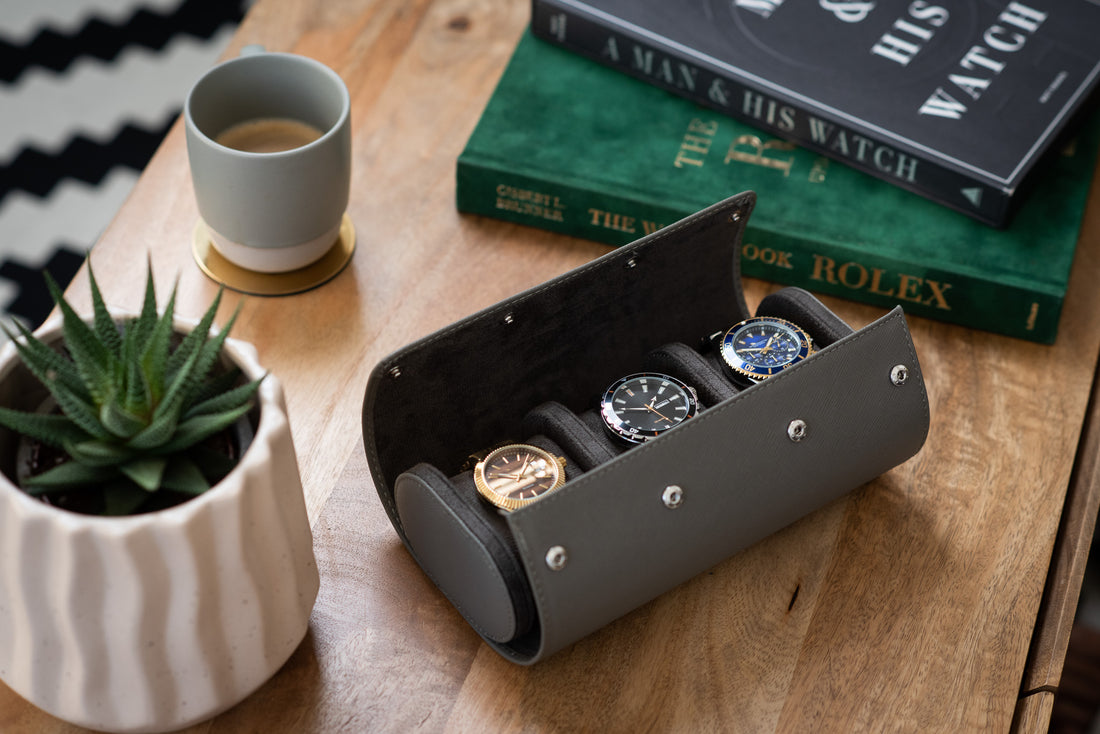 Gray watch roll opened on a table  with three watches inside 