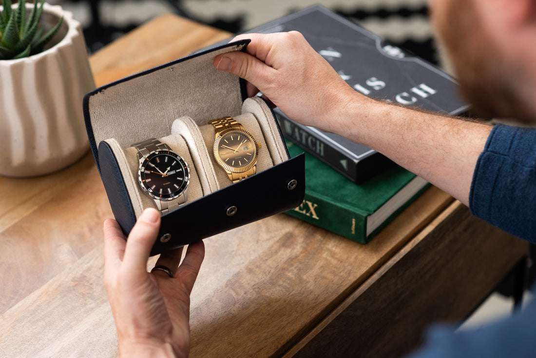 Blue watch roll case on a table with two watches inside