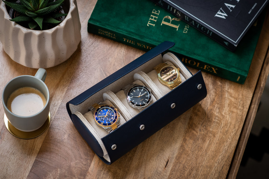  A blue leather watch roll with three watches inside. The watches are a Rolex Oyster Perpetual Datejust, a Rolex Submariner, and a Rolex Daytona. 