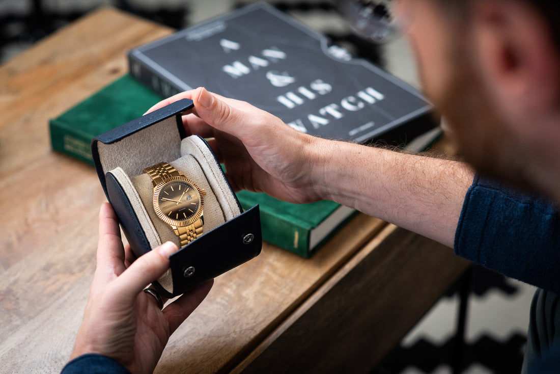 A man holding an open watch roll and staring at it