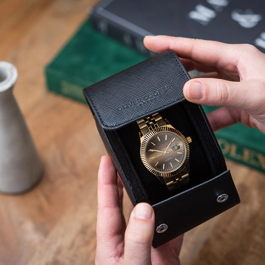 Man holding a single watch roll case with a gold watch, featuring genuine leather construction