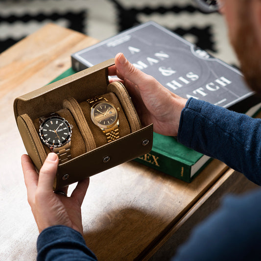 An individual proudly displaying an Oliver Cooper watch roll case in rich brown, featuring his impressive watch collection