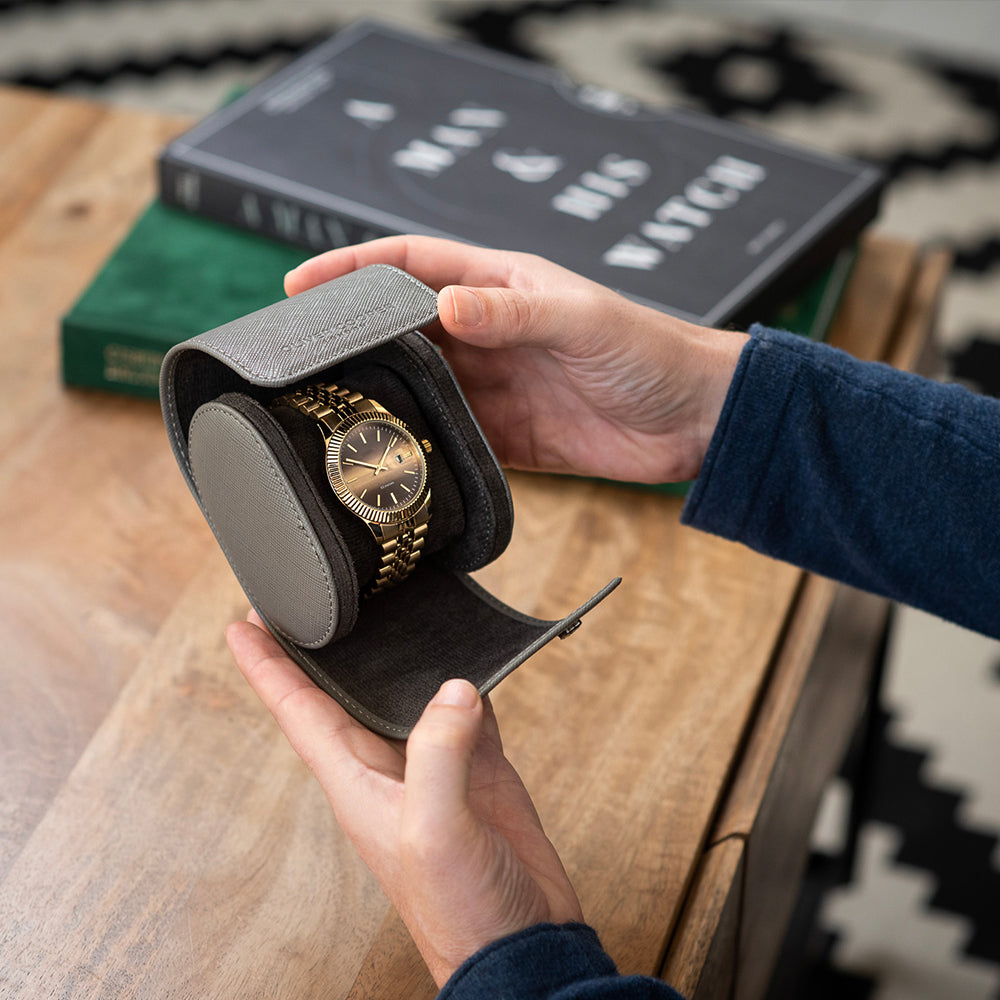 Man holding a gold watch in an Oliver Cooper London watch roll case, featuring real leather and soft suede lining.